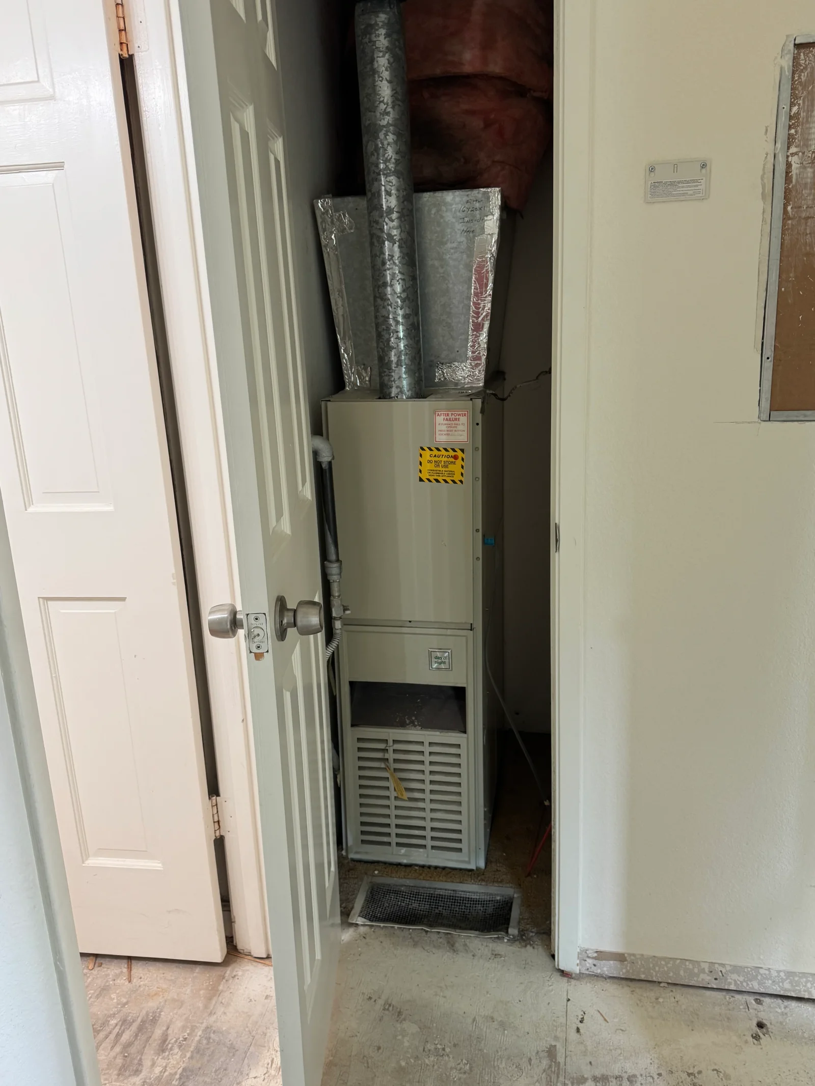 Beige Day & Night furnace in a closet with galvanized steel ductwork, foil-wrapped plenum, and pink fiberglass insulation